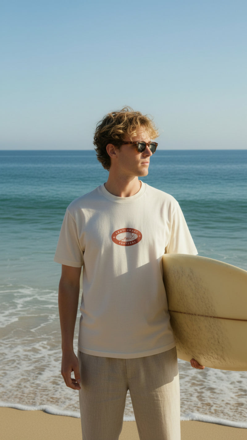 Man holding a surfboard on a beach with ocean in the background